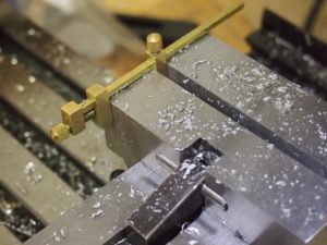 We attached a brass clamp to the vise in the vertical mill to create an improvised "mill stop". This allowed us to drill many highly repeatable accurate holes very quickly.