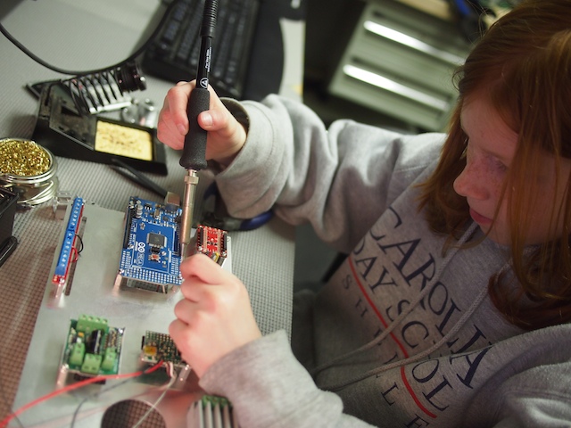 Genevieve is soldering the various components to the Arduino Mega microcontroller.