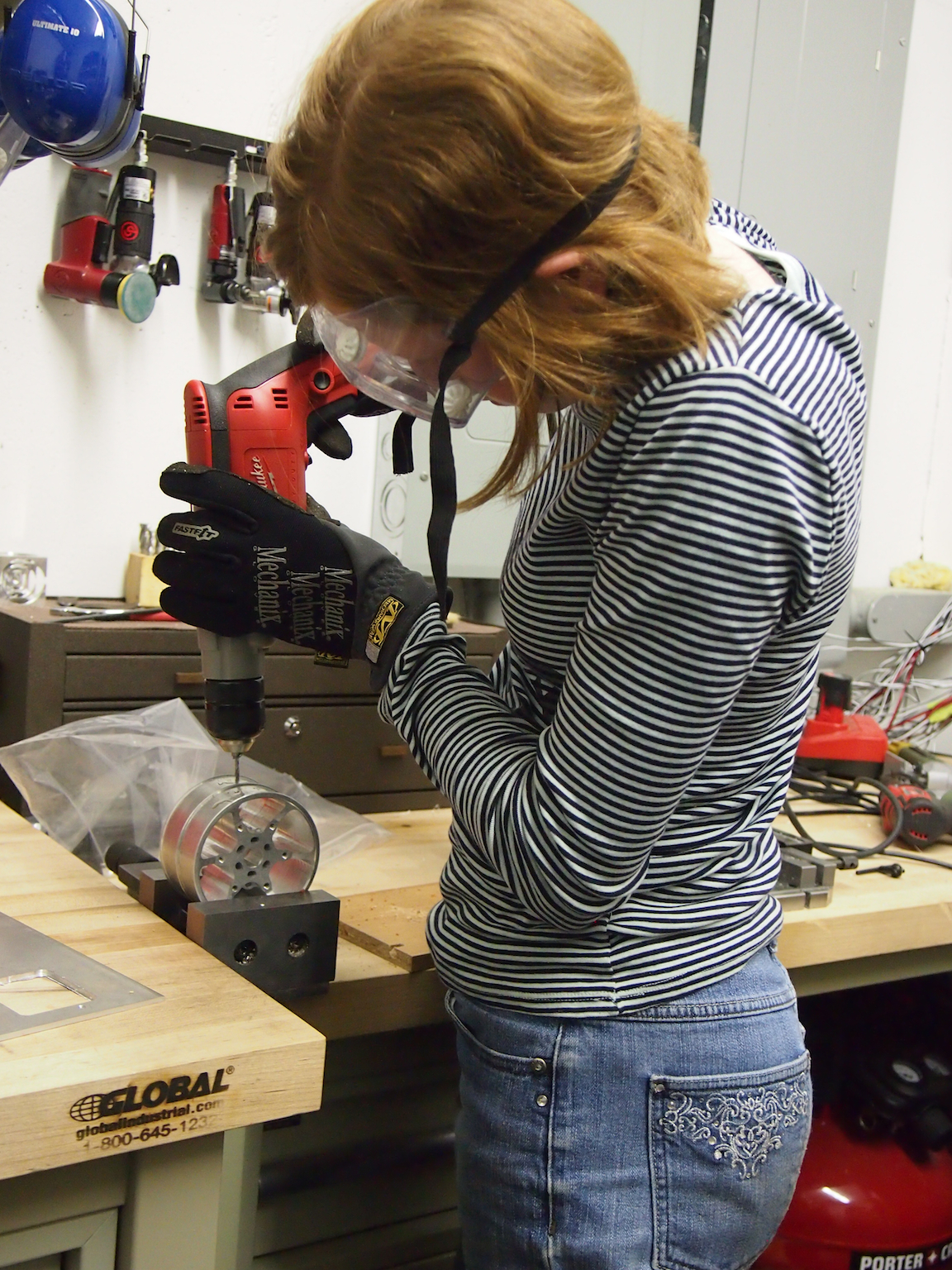 A new skill: Camille uses our largest Milwaukee hand drill to tap 6-32 threads into the metal wheels. The threaded holes will be used to secure the tread to the wheel (we don't like glue).