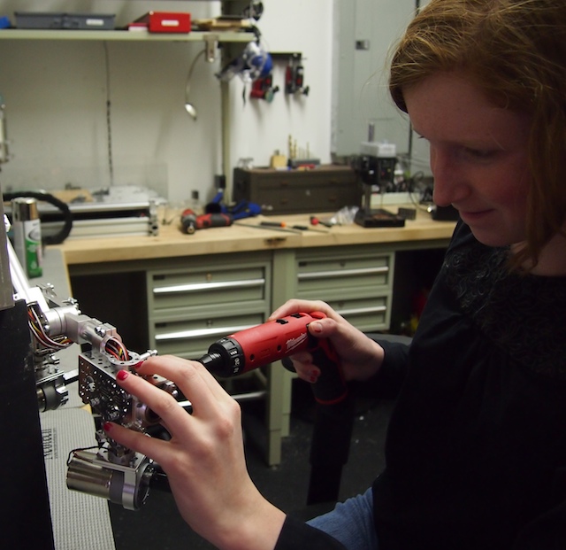 Camille uses her new power driver to work on the robot's chassis.